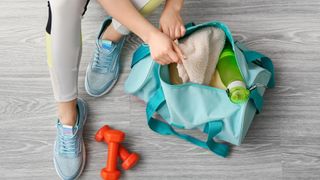 person sat on floor opening one of the best gym bags 