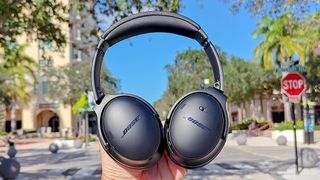 Listing image for best Bose headphones showing Bose QuietComfort headphones held up against a blue sky