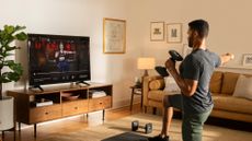 Man doing a Peloton strength training workout with dumbbells at home