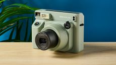 A sage green Fujifilm Instax Wide 400 instant camera